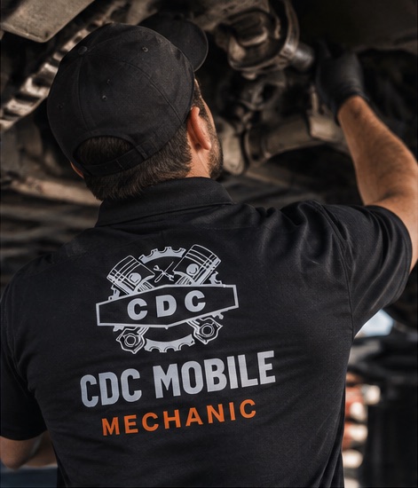 CDC Mobile mechanic working beneath a vehicle in branded uniform